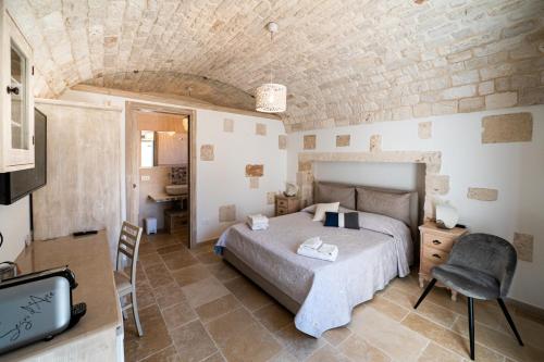um quarto com uma cama e uma cadeira num quarto em Bed and Breakfast Trulli San Leonardo em Alberobello