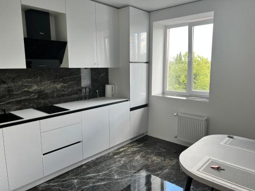 una cocina con armarios blancos, una ventana y una mesa en Люкс апартаменти в ЖКАрена, en Rivne