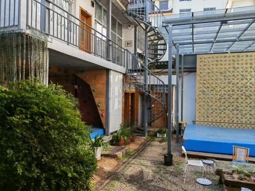 a courtyard of a building with a blue bed and stairs at Lijiang Adventure Inn in Lijiang