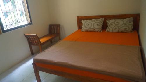 a bedroom with a bed and a chair and a window at Griya Harja Homestay in Borobudur