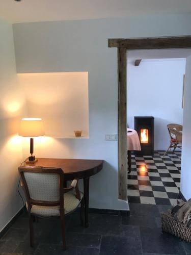 a room with a table and a chair and a fireplace at La Petite Maison Blanche in Wanze