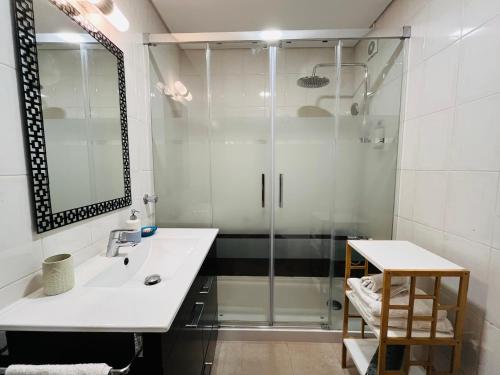 een badkamer met een glazen douche en een wastafel bij Casa do Mar in Costa da Caparica