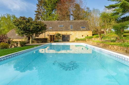 a swimming pool in front of a house at Les Bambous, avec piscine, tennis et lac privatif in Guerquesalles