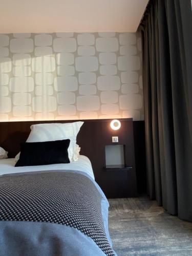 a bedroom with a bed with a light above it at Hotel du Pasino in Saint-Amand-les-Eaux