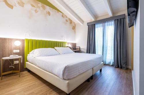 a bedroom with a white bed and a green wall at Hotel Regina Elena 57 & Oro Bianco SPA in Rimini