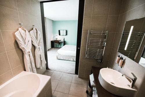 ein Badezimmer mit einem Waschbecken, einem WC und einem Spiegel in der Unterkunft Hotel du Pasino in Saint-Amand-les-Eaux