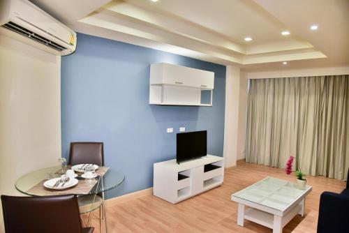 a living room with a glass table and a television at The Kaze 34 Hotel and Serviced Residence in Bangkok
