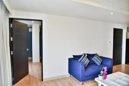 a living room with a blue couch and a table at The Kaze 34 Hotel and Serviced Residence in Bangkok