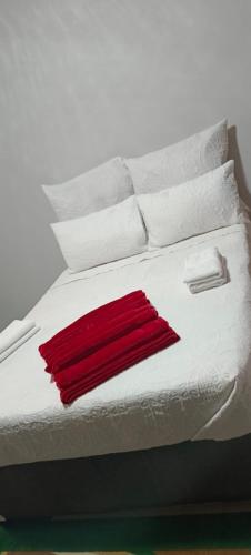 a white bed with white pillows and a red blanket at Sunset Guest House in Roodepoort