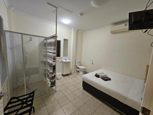 1 dormitorio con cama, ducha y aseo en Clermont Hotel Motel en Clermont