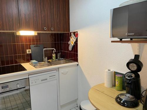 Il comprend une petite cuisine avec un évier et une télévision. dans l'établissement La Grande Motte - 2 pièces avec terrasse, 5 couchages, parking en option - FR-1-790-4, à La Grande Motte