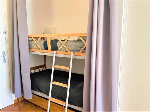Cette chambre comprend 2 lits superposés avec des rideaux violets. dans l'établissement Studio Cabine à La Grande Motte - Plage Proche, Climatisé, Terrasse, Parking - FR-1-790-8, à La Grande Motte