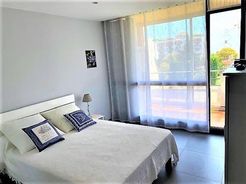 une chambre avec un lit blanc et une grande fenêtre dans l'établissement Bel Appartement 1 Chambre à La Grande-Motte avec Loggia et Parking, Proche Plage et Centre - FR-1-790-25, à La Grande Motte