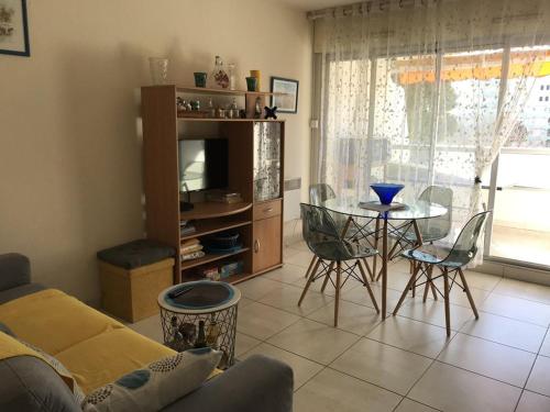 un salon avec une télévision, une table et des chaises dans l'établissement Appartement Climatisé à La Grande Motte - 2 Pièces Cabine, Piscine, Parking Privé - FR-1-790-26, à La Grande Motte