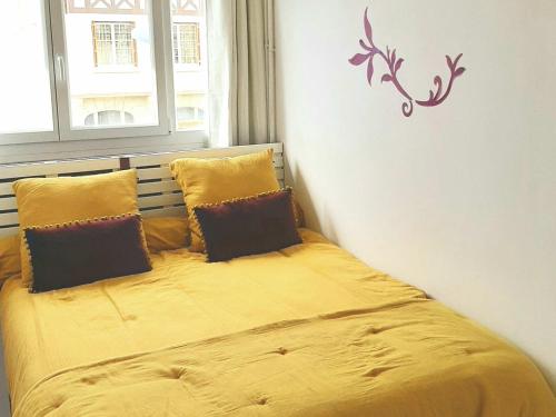 une chambre avec un lit avec des draps et des oreillers jaunes dans l'établissement Appartement refait à neuf, proche commerces, parking privé - FR-1-712-82, à Villers-sur-Mer