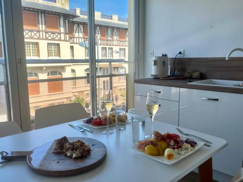 une table avec une assiette de nourriture et des verres de vin dans l'établissement Appartement refait à neuf, proche commerces, parking privé - FR-1-712-82, à Villers-sur-Mer