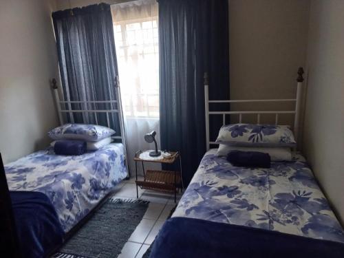a bedroom with two beds and a window at Wildepeer in Nelspruit