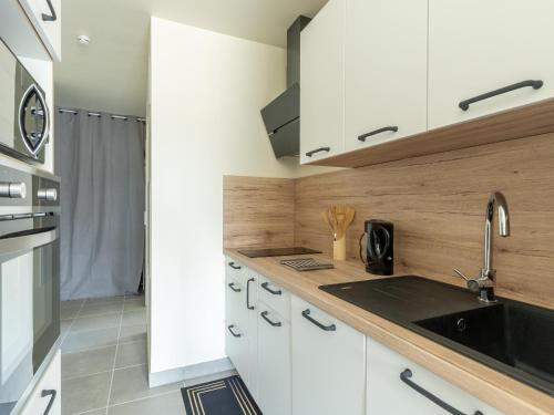 une cuisine avec des armoires blanches et un évier dans l'établissement Bel appartement neuf à Mimizan Plage, 400m de l'océan, 2 étoiles, 4 pers, parking, balcon, tout équipé - FR-1-50-136, à Mimizan
