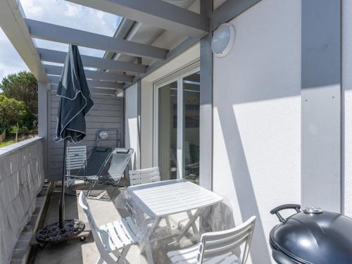un patio avec une table, des chaises et un parasol dans l'établissement Bel appartement neuf à Mimizan Plage, 400m de l'océan, 2 étoiles, 4 pers, parking, balcon, tout équipé - FR-1-50-136, à Mimizan