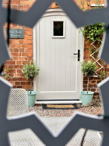 a white door with potted plants in front of a house at The Old Rectory Tack Rooms in Shrewsbury