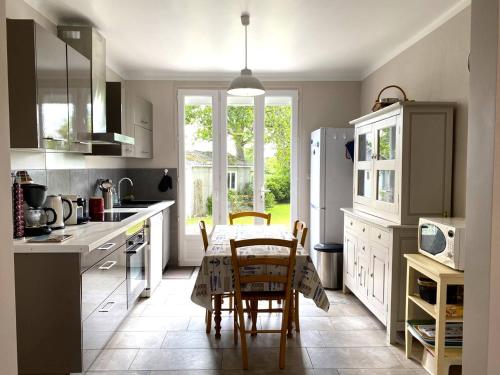 Il comprend une cuisine équipée d'une table et de chaises. dans l'établissement Charmante maison rénovée à Trébeurden avec jardin clos, terrasse et parking, à 1km de la mer - FR-1-368-423, à Trébeurden