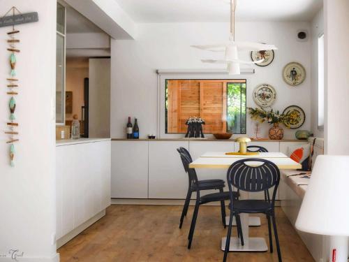 une cuisine avec des armoires blanches et une table et des chaises dans l'établissement Superbe maison rénovée, 250m de l'océan, 12 pers, terrasse, jardin, proche plage Kerleven et golf - FR-1-481-164, à La Forêt-Fouesnant