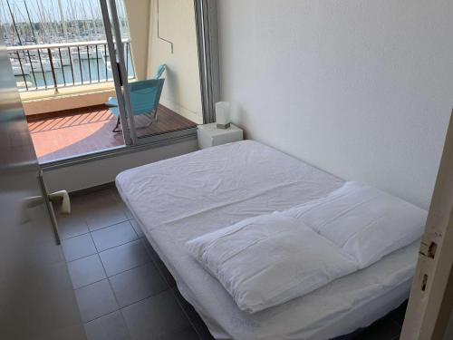 Cette chambre comprend un lit blanc et un balcon. dans l'établissement Port Camargue : Charmant T3 refait, 100m plage, piscine privée, parking, pour 4 pers. - FR-1-731-70, au Grau-du-Roi