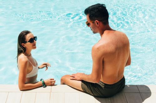 a man and a woman sitting next to a swimming pool at Hotel Regina Elena 57 & Oro Bianco SPA in Rimini