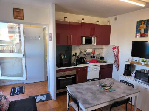 - une cuisine avec des placards rouges et une table dans une pièce dans l'établissement chantrelle, à Saint-Cyprien