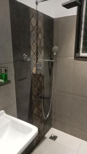 a shower in a bathroom with a glass door at Mayilveedu Guest House in Tuticorin