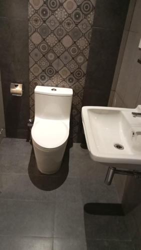 a bathroom with a white toilet and a sink at Mayilveedu Guest House in Tuticorin
