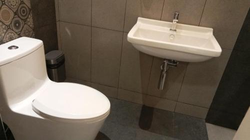 a bathroom with a white toilet and a sink at Mayilveedu Guest House in Tuticorin
