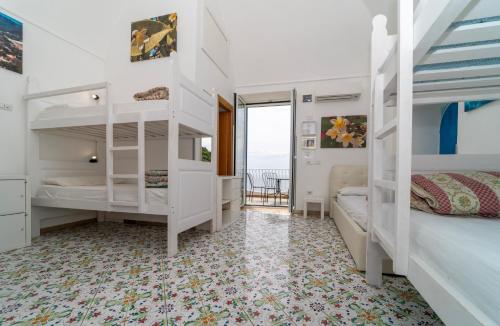 a bedroom with white bunk beds and a balcony at Hostel Brikette in Positano