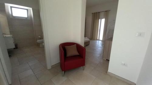 a red chair sitting on a tile floor in a room at B&B Bonomi in Torre Lapillo