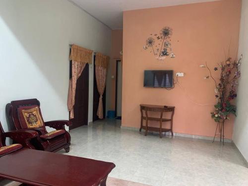 a living room with chairs and a tv on the wall at Homestay Kuala Terengganu Pak Latif in Kuala Terengganu