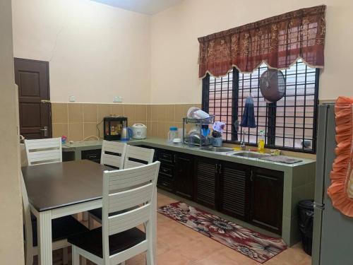 a kitchen with a table and a sink and a table and chairs at Homestay Kuala Terengganu Pak Latif in Kuala Terengganu