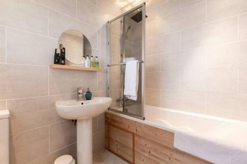 a bathroom with a sink and a mirror and a tub at Chalet Ruan Montriond - Mountain Voyages in Montriond