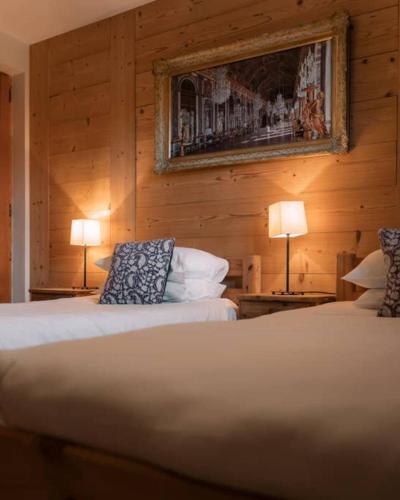 two beds in a room with wooden walls and two lamps at Chalet Ruan Montriond - Mountain Voyages in Montriond