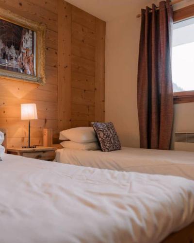 a bedroom with two beds and a window at Chalet Ruan Montriond - Mountain Voyages in Montriond