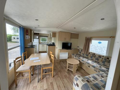 eine Wohnwagen-Küche und ein Esszimmer mit einem Tisch und Stühlen in der Unterkunft Camping L'Orée des Caps in Licques