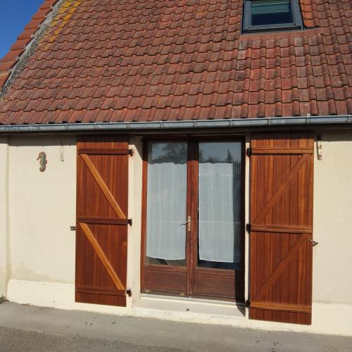 une maison avec des portes en bois et un toit rouge dans l'établissement Maison de l'épinette au calme en bord de mer, à Cayeux-sur-Mer