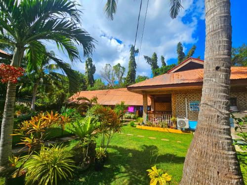 a house with a palm tree in the yard at Bohol Sea Breeze Cottages and Resort in Panglao
