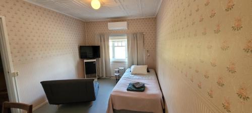 a room with a bed and a chair and a tv at Liekorannan Majatalo- kodinomaista majoitusta rautatieasemaa vastapäätä in Sastamala