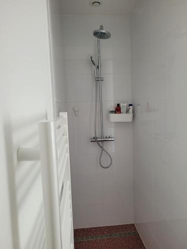 La salle de bains blanche est pourvue d'une douche avec un pommeau de douche. dans l'établissement Pause Uzètienne, à Uzès