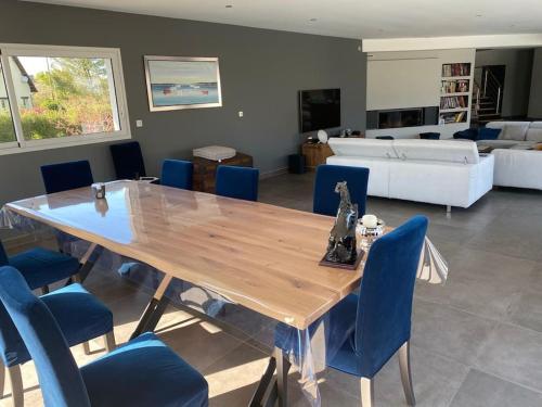 une salle à manger avec une table en bois et des chaises bleues dans l'établissement Villa avec piscine, à Janville