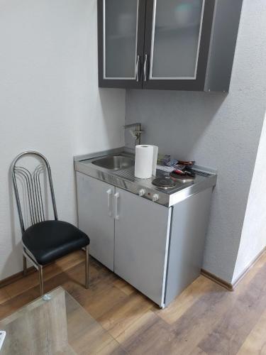 a small kitchen with a sink and a chair at Pansion Panonika 2 in Tuzla
