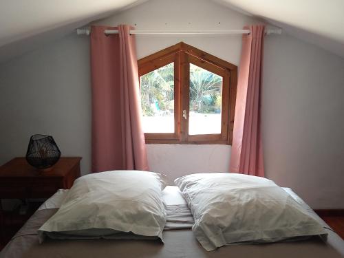 a bedroom with a window and two pillows on a bed at Espace Détente des Calumets in Saint-Paul
