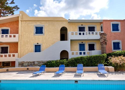 a villa with a swimming pool and blue chairs at Niros Beachfront Aparthotel in Kokkíni Khánion