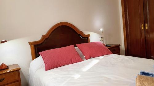 een bed met twee rode kussens erop bij Apartamento Vacacional La Rula in Llanes