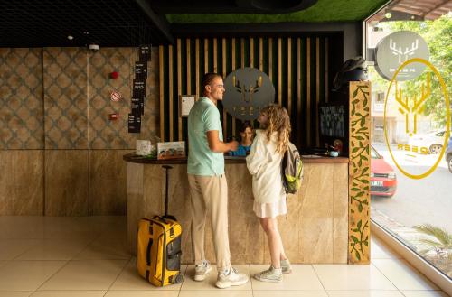 een man en een meisje die aan een toonbank staan bij Deer Hostel & Hotel in Antalya